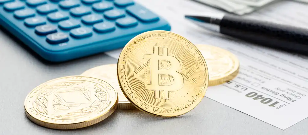 Bitcoin érme adóbevallási űrlapon és kalkulátor mellett, utalva a kriptovaluták adózására