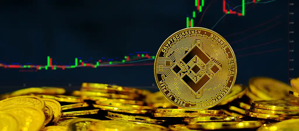 Binance érme halmozott érmékkel és árfolyam grafikonokkal a háttérben
