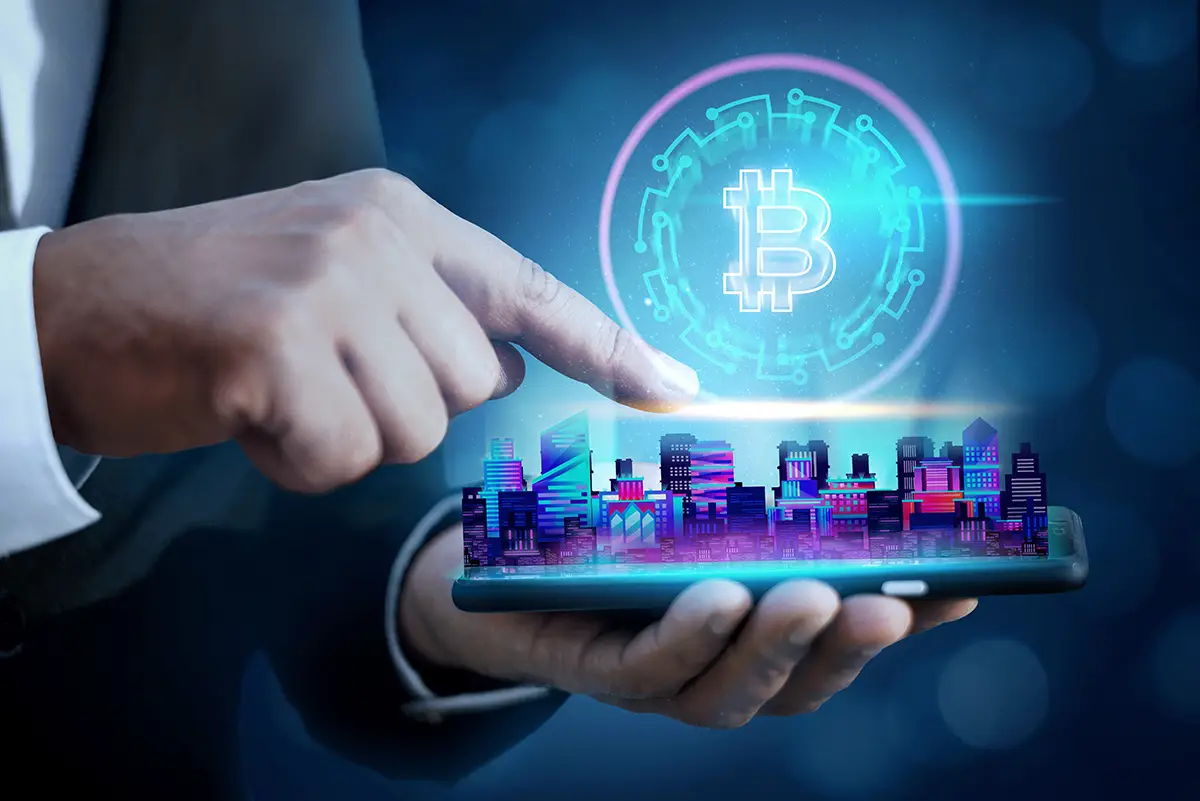 Üzletember kézben tartott okostelefonnal, amelyből digitális város és lebegő Bitcoin szimbólum emelkedik ki, a kriptovaluta marketing világát jelképezve.